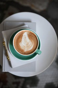 Cup and saucer resting on a stack of small notebooks