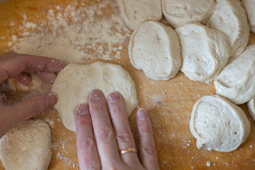 Woman hands preparing slices of dough on a wooden board