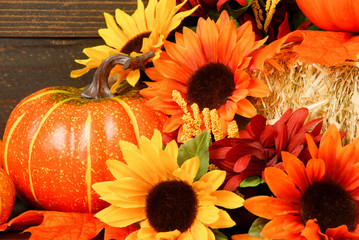 Fall decoration of Sunflowers, Mum flowers pumpkins and gourds arranged on bale of hay, Thanksgiving still life with rustic wooden background, fall background