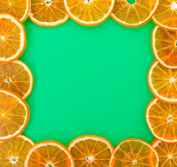 Christmas greeting card. Square made of dried slices of oranges on a green background. Top view, copy space.