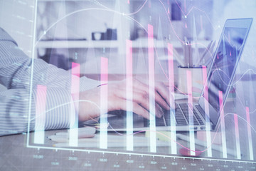 Double exposure of stock market graph with man working on laptop on background. Concept of financial analysis.