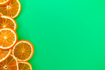 Christmas greeting card. Slices of dried oranges in the left side on a green background. Top view, copy space.