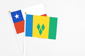 Saint Vincent And The Grenadines and Chile stick flags on white background. High quality fabric, miniature national flag. Peaceful global concept.White floor for copy space.