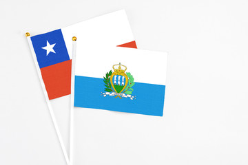 San Marino and Chile stick flags on white background. High quality fabric, miniature national flag. Peaceful global concept.White floor for copy space.