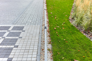 Styling paving slabs. Red paving slab next to a luxurious green lawn.