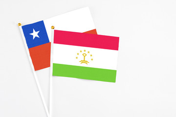 Tajikistan and Chile stick flags on white background. High quality fabric, miniature national flag. Peaceful global concept.White floor for copy space.