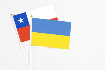 Ukraine and Chile stick flags on white background. High quality fabric, miniature national flag. Peaceful global concept.White floor for copy space.