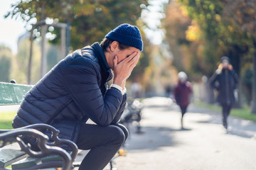 Worried young man on a bench during autumn day