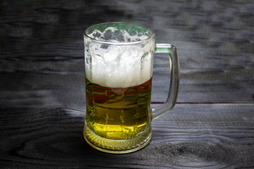 glass of beer on a dark wooden background, foamy beer