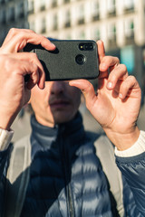 Young man taking a photo with his mobile phone in a european city
