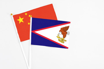 American Samoa and China stick flags on white background. High quality fabric, miniature national flag. Peaceful global concept.White floor for copy space.