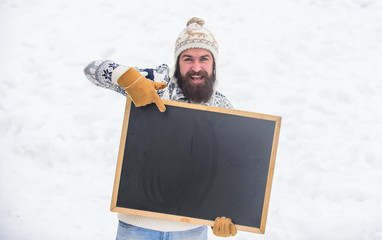 look here. bearded man in warm clothes. Happy new year. happy hipster with blackboard. man...