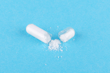 one open capsule of nutritional supplement msm, sulfur, on blue background