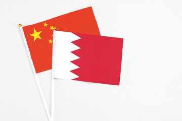 Bahrain and China stick flags on white background. High quality fabric, miniature national flag. Peaceful global concept.White floor for copy space.