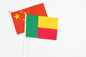 Benin and China stick flags on white background. High quality fabric, miniature national flag. Peaceful global concept.White floor for copy space.