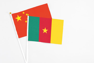 Cameroon and China stick flags on white background. High quality fabric, miniature national flag. Peaceful global concept.White floor for copy space.