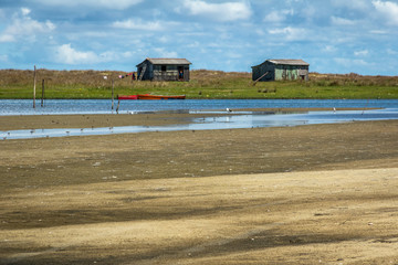 Sand track in pond with wooden fisherman's house in the background