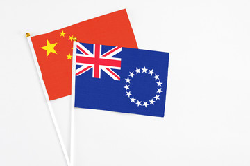 Fototapeta premium Cook Islands and China stick flags on white background. High quality fabric, miniature national flag. Peaceful global concept.White floor for copy space.