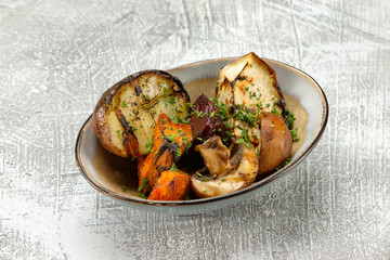 Closeup plate of grilled vegetables - potato, mushrooms, pumpkin and squash at concrete table background.