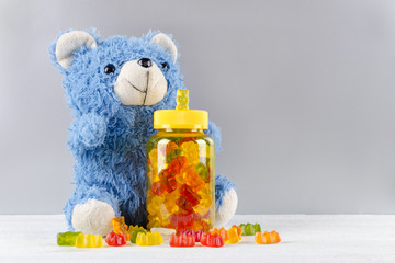 vitamins for children like jelly candy and teddy bear on gray background