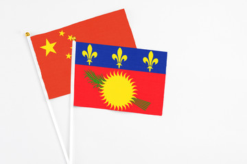 Guadeloupe and China stick flags on white background. High quality fabric, miniature national flag. Peaceful global concept.White floor for copy space.