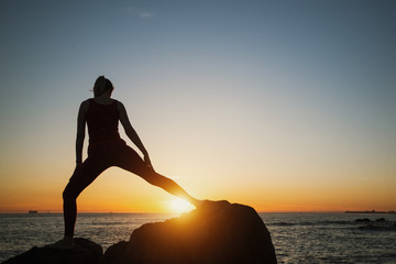 Silhouette of yoga woman on the Sea beach at sunset.