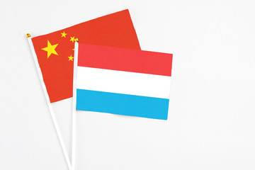 Luxembourg and China stick flags on white background. High quality fabric, miniature national flag. Peaceful global concept.White floor for copy space.