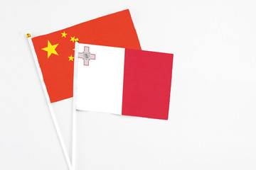 Malta and China stick flags on white background. High quality fabric, miniature national flag. Peaceful global concept.White floor for copy space.