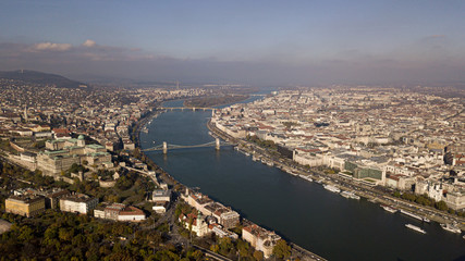 Obraz premium The highest point of Budapest with a view of the city panorama. A river with bridges and ships. Sunset sun. Chain bridge, palace and parliament. Top view.