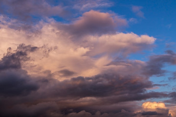 Naklejka na ściany i meble Dramatic colorful cumulus stormclouds at sunset sky, heaven