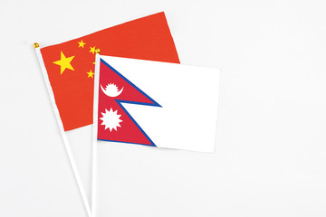 Nepal and China stick flags on white background. High quality fabric, miniature national flag. Peaceful global concept.White floor for copy space.