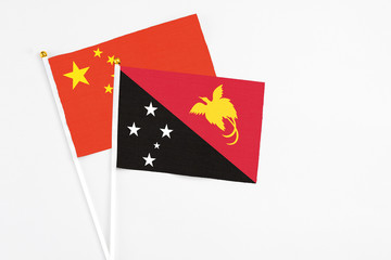 Papua New Guinea and China stick flags on white background. High quality fabric, miniature national flag. Peaceful global concept.White floor for copy space.