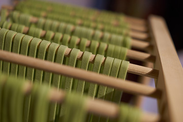Naklejka premium Grüne Nudeln Tagliatelle mit Spinatfärbung beim Trocknen auf Holzständer