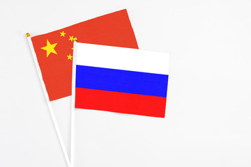 Russia and China stick flags on white background. High quality fabric, miniature national flag. Peaceful global concept.White floor for copy space.