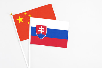 Slovakia and China stick flags on white background. High quality fabric, miniature national flag. Peaceful global concept.White floor for copy space.