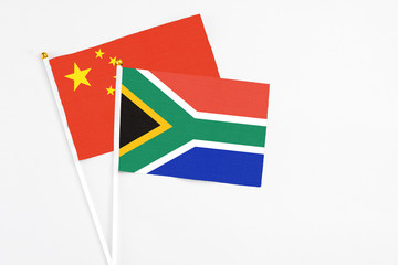 South Africa and China stick flags on white background. High quality fabric, miniature national flag. Peaceful global concept.White floor for copy space.