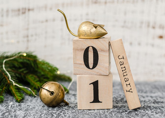 Chinese New Year 2020. Date January 1 on a wooden calendar with metal rat and christmas bell and twigs of a Christmas tree on agrey background. New Year of the rat.