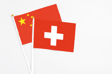 Switzerland and China stick flags on white background. High quality fabric, miniature national flag. Peaceful global concept.White floor for copy space.