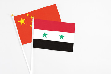 Syria and China stick flags on white background. High quality fabric, miniature national flag. Peaceful global concept.White floor for copy space.
