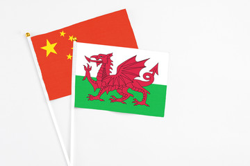 Wales and China stick flags on white background. High quality fabric, miniature national flag. Peaceful global concept.White floor for copy space.