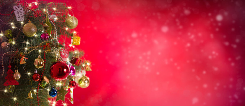 Christmas and New Year background. Pine tree and Christmas decorations on red bokeh background