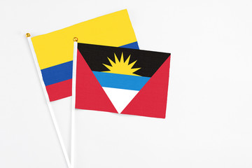 Antigua and Barbuda and Colombia stick flags on white background. High quality fabric, miniature national flag. Peaceful global concept.White floor for copy space.