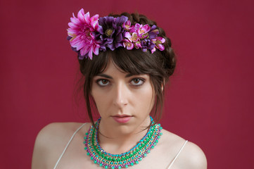 Young woman dancing with white dress and flowers in her hair. Red background.