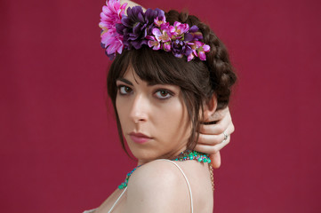 Young woman dancing with white dress and flowers in her hair. Red background.