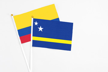 Curacao and Colombia stick flags on white background. High quality fabric, miniature national flag. Peaceful global concept.White floor for copy space.
