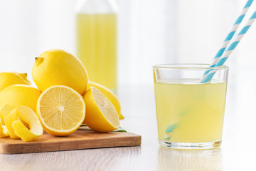 A glass of lemon juice and lemons around on a table.