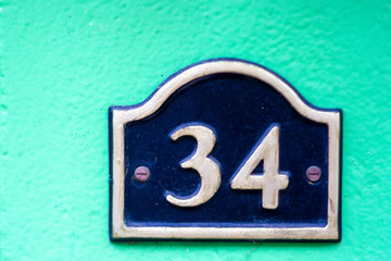 House number 34 on a very bright and light green wall