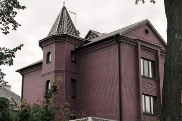 Old brick church. Facade of an old building of brown brick on a background of gray sky