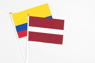 Latvia and Colombia stick flags on white background. High quality fabric, miniature national flag. Peaceful global concept.White floor for copy space.