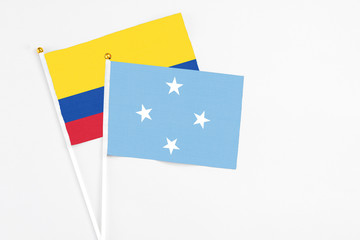 Micronesia and Colombia stick flags on white background. High quality fabric, miniature national flag. Peaceful global concept.White floor for copy space.